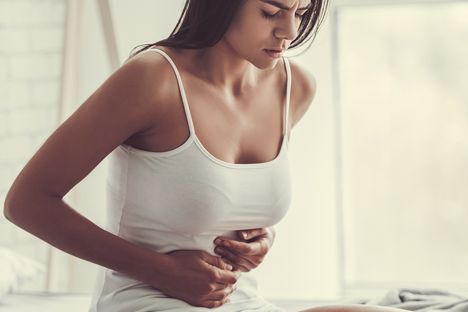 Eine Frau hält ihren Bauch. Eine Behandlung mit Fremdstuhl kann bei chronisch-entzündlichen Darmerkrankungen wie der mikroskopischen Kolitis helfen.